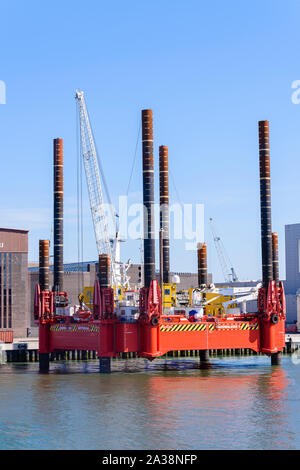 Eine schwimmende Konstruktion Lastkahn mit Kran und Greifer, hat vier seiner acht Spud - Beine runter, es auf dem Meeresboden zu ruhen, während er Dredgen. Hafen Stockfoto