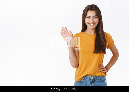 Freundlich fröhlich, glücklich lächelnde Frau, sie winken mit der erhobenen Hand. Attraktives Mädchen gruss Freund, Hallo oder Hi, willkommen Gast, Weiß Stockfoto