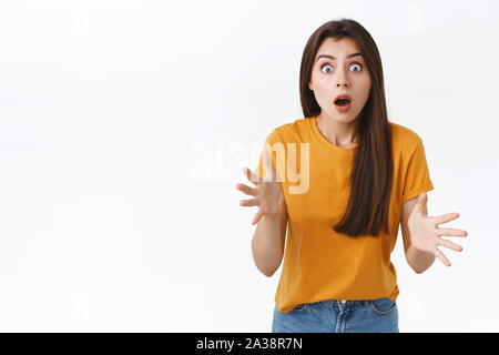 Erschrocken, erstaunt und sprachlos brünette Frau, Kiefer und schnappte erstaunt, starren Kamera beeindruckt, Hände schüttelte, beeindruckt oder mit den Betroffenen Stockfoto