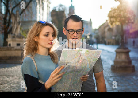 Touristen auf der Suche nach der Karte auf Papier und auf der Suche nach Richtung früh morgens auf leeren alten Platz irgendwo in Europa Stockfoto