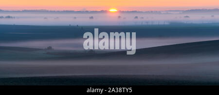 Sonnenaufgang über Felder erinnert an die Italienische Landschaft der Toskana auf einem wunderschönen Nebligen Morgen Stockfoto