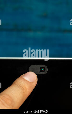 Kamera Datenschutz Schieben Sie mit einem Finger mit einer blauen Wand. Stockfoto