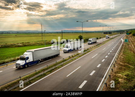 Lkw Lkw in einen Wohnwagen oder ein Konvoi auf Land Autobahn unter einem schönen Himmel Stockfoto