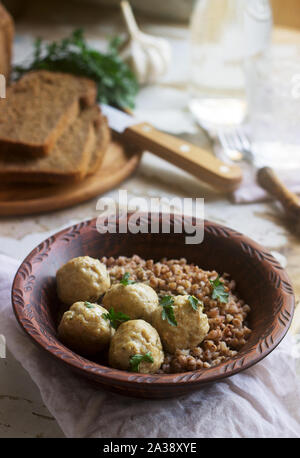 Fleischbällchen in saurer Sahne-Sauce, serviert mit Buchweizenbrei, Brot und Knoblauch. Rustikaler Stil. Stockfoto
