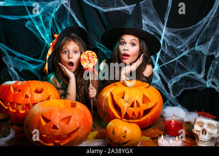 Mutter und ihrer Tochter in Hexe Kostüme Halloween Feiern mit Halloween Süßigkeiten und süße über Spider web Stockfoto
