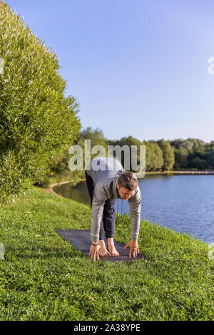 Man Yoga Asanas im City Park inspiriert. Fitness im Freien und Life Balance Konzept. Stockfoto