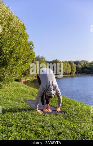 Man Yoga Asanas im City Park inspiriert. Fitness im Freien und Life Balance Konzept. Stockfoto