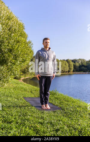 Man Yoga Asanas im City Park inspiriert. Fitness im Freien und Life Balance Konzept. Stockfoto