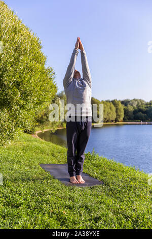 Man Yoga Asanas im City Park inspiriert. Fitness im Freien und Life Balance Konzept. Stockfoto