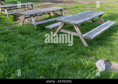 Picknick Bänke auf dem Gras in einer Reihe warten auf einige Leute Urlaub auf dem Campingplatz zu genießen Stockfoto