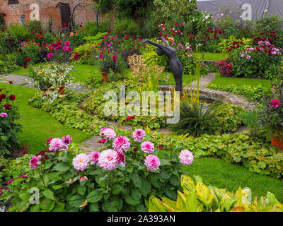 Chenies Manor Sunken Garden Zierteich mit Alan Biggs Skulptur in der Mitte mit Dahlie 'Creme de Cassis', 'Labyrinth' und verschiedenen Laub. Stockfoto