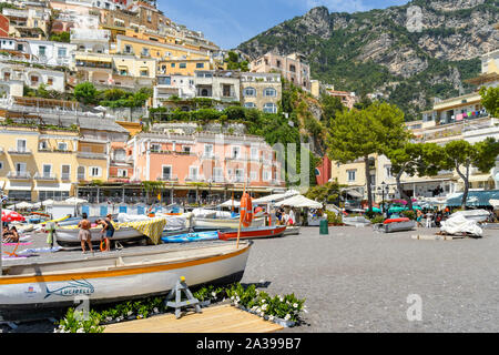 POSITANO, ITALIEN - AUGUST 2019: Boote am Strand von Positano. Im Hintergrund sind die farbigen Gebäude auf dem Hügel mit Blick auf den Strand Stockfoto