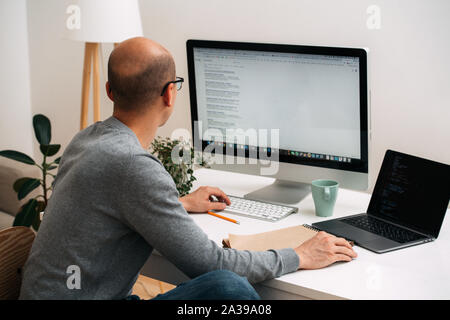 Programmierer, die Arbeit hinter dem Schreibtisch, googeln und Codierung gleichzeitig Stockfoto