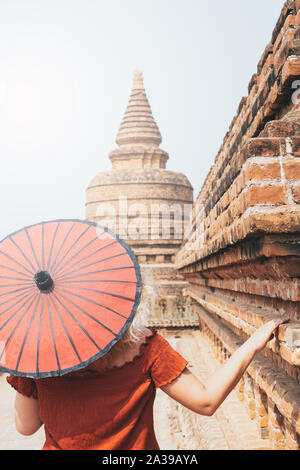 Frau mit traditionellen burmesischen roten Regenschirm mit Blick auf die Pagode und Tempel der alten Bagan in Myanmar Stockfoto
