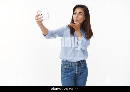 Pflege angebot ziemlich erwachsenen Frau Küsse via Smartphone Video - Anruf senden, Gesprächspartner, wobei flirty selfie, Schlag mwah halten Handy, gadget Blick Stockfoto