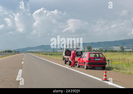 Vranje, Serbien. Juni 23, 2019: Abschleppdienst Arbeiter wird alte beschädigt Auto auf Abschleppwagen auf der Autobahn zu laden. Alten roten Volkswagen Golf Stockfoto