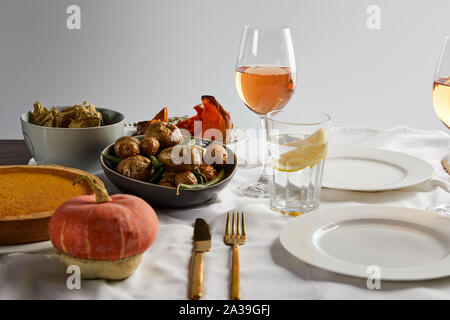 Gebackene Gemüse, Kürbis Pumpkin Pie und ganz in der Nähe von Gläsern mit Rose Wein und Zitronensaft Wasser isoliert auf Grau Stockfoto
