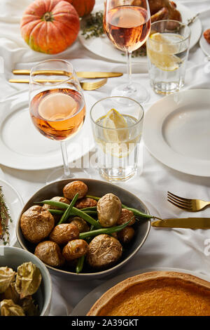 Festliche Abendessen mit gebackenem Gemüse der Saison in der Nähe von Gläsern mit Rose Wein und Zitronensaft Wasser serviert auf der weißen Tischdecke Stockfoto