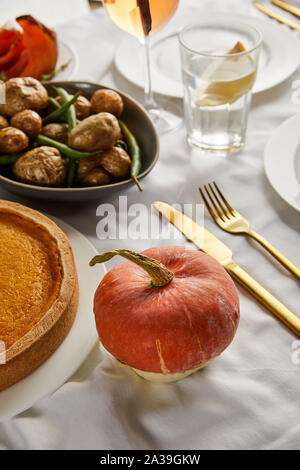 Gebackene Kartoffeln und Pumpkin Pie in der Nähe der ganzen Kürbis auf weißen Tischdecke Stockfoto