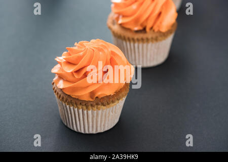 Köstliche Halloween orange Cupcakes auf schwarzem Hintergrund Stockfoto