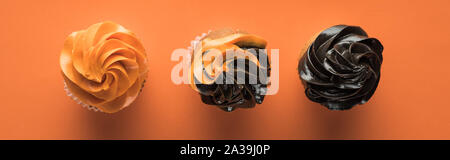 Blick von oben auf die köstliche Halloween Cupcakes auf orangem Hintergrund, Panorama-Aufnahme ein. Stockfoto