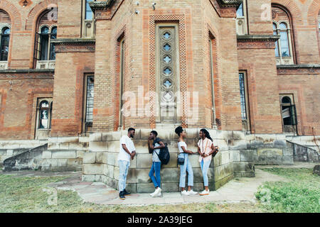 Gruppe von fröhlichen happy Studenten auf weiße Wand im Campus lehnend. Internationale Ausbildung Konzept Stockfoto