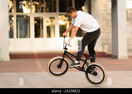 Der Kerl fährt auf dem BMX, stehend auf das Hinterrad. Stockfoto