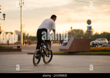 Der Kerl reitet ein BMX Fahrrad die Straße runter. Stockfoto