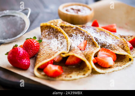 Französische Crepes mit Nutella und Erdbeeren, Leckere süße Nachspeise mit Schokolade und Sahne frische Erdbeeren Obst gefüllt Stockfoto