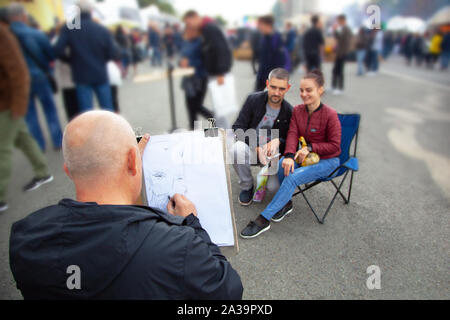 Chisinau, Moldawien - 5. Oktober 2019: Maler (Künstler) zeichnet ein Porträt (Karikatur) von einem Mann und einer Frau. Stockfoto