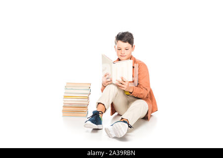 Fokussierte kid im casual Outfit lesen Buch auf Weiß Stockfoto