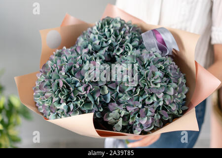 Blumenstrauß aus violetten und grünen Blumen. Wunderschöne Hortensienblüten in womans Hände. Die Arbeit der Florist in einem Blumenladen. Frische Schnittblume. Stockfoto