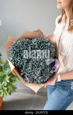 Blumenstrauß aus violetten und grünen Blumen. Wunderschöne Hortensienblüten in womans Hände. Die Arbeit der Florist in einem Blumenladen. Frische Schnittblume. Stockfoto