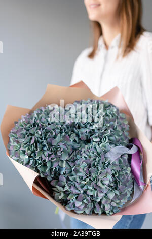 Blumenstrauß aus violetten und grünen Blumen. Wunderschöne Hortensienblüten in womans Hände. Die Arbeit der Florist in einem Blumenladen. Frische Schnittblume. Stockfoto