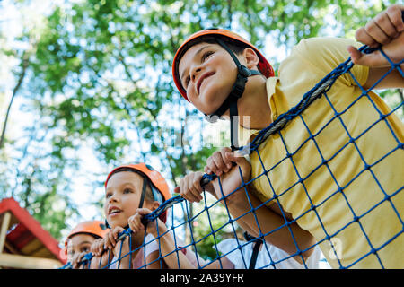 Low Angle View von lächelnden Kinder in orange Helme Happy Boy im Adventure Park Stockfoto