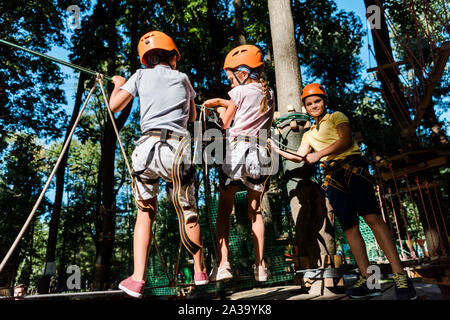 Multikulturelle Jungen in Helme in der Nähe von Freund auf hohem Seil Trail Stockfoto