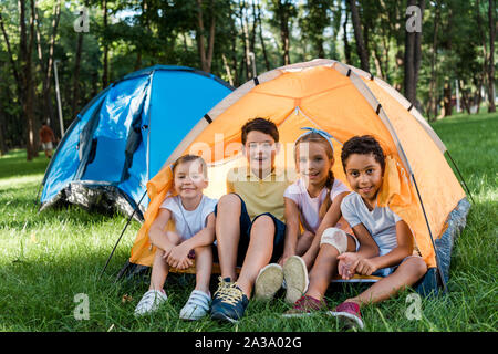 Multikulturelle Kinder glücklich lächelnd, während Gelb Lager sitzen Stockfoto