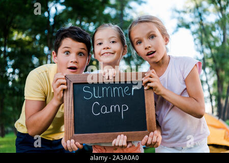 Überrascht Kinder holding Kreidetafel mit Summer Camp Buchstaben Stockfoto