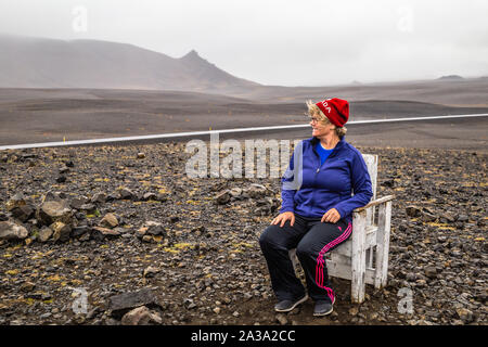 Frau sitzt auf Stuhl bei Rastplatz an wüst Lavafeld Landschaft im Norden Island suchen Stockfoto