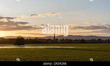 Sonnenuntergang über eine überschwemmte Wiese, an einem Oktoberabend. Mit einem Kirchturm Silhouette gegen den Himmel. Mit der Malvern Hills im Hintergrund. Upton Stockfoto