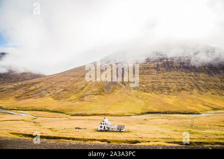 Typisches Haus in der Landschaft mit Bergen an einem bewölkten Tag in Island Stockfoto