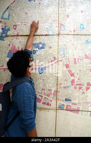 Ein tunesischer student Punkte auf einer alten Landkarte der Medina von Tunis in ein architektonisches Erbe Organisation im alten Viertel der Stadt, Tunesien. Stockfoto