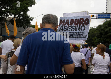 Die Demonstranten die Teilnahme an der Veranstaltung "die Mutter aller Proteste in Venezuela gegen Nicolas Maduro Regierung mit einem Board, das liest assassi Stockfoto