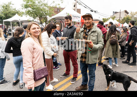 New York, NY - Oktober 6, 2019: Festivalbesucher genießen essen Pizza während der New York Pizza Festival in der Crescent Avenue in der Bronx Stockfoto