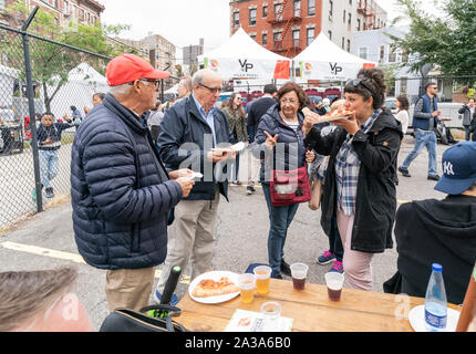 New York, NY - Oktober 6, 2019: Festivalbesucher genießen essen Pizza und Trinken während New York Pizza Festival in der Crescent Avenue in der Bronx Stockfoto
