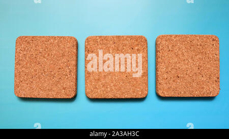 3 square Korkfliesen in einer Reihe nebeneinander anordnen, mit einem blauen Hintergrund. Stockfoto