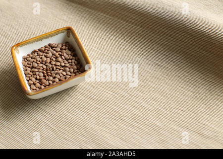 Gesundes Essen Linsen in eine Schüssel auf beiger Stoff Hintergrund Stockfoto