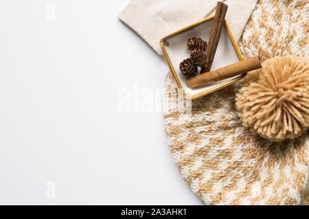 Strickmütze und Tannenzapfen und zimtstangen in einer Schüssel auf weißem Hintergrund. Herbst Konzept Stockfoto