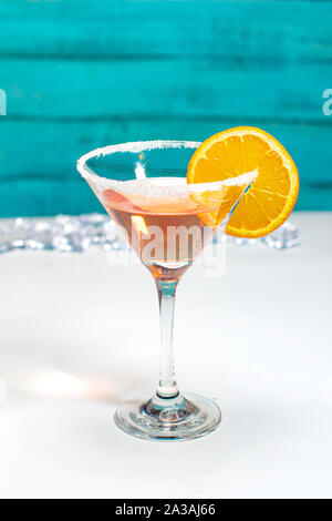 Cocktail mit orange garnieren mit einem grünen Holz- wand und weißer Tisch Stockfoto