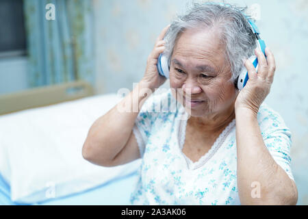 Asiatische Senior oder ältere alte Dame Frau Patienten Musik hören, während Sie auf dem Bett in der Krankenpflege Krankenhaus liegen: Gesunde starke medizinisches Konzept Stockfoto